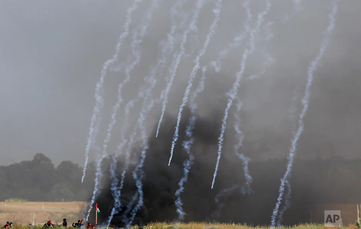 Teargas canisters fired by Israeli troops falls down at Palestinians during a demonstration near the Gaza Strip border with Israel, in eastern Gaza City, Friday, March 30, 2018.(AP Photo/Hatem Moussa)