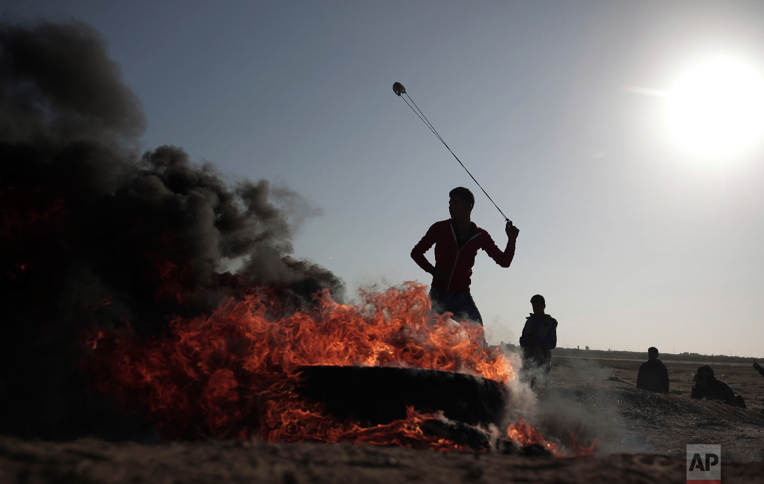  A Palestinian protester hurls stones toward Israeli soldiers during a protest near the Gaza Strip border with Israel, in eastern Gaza City, Saturday, March 31, 2018. (AP Photo/ Khalil Hamra) 