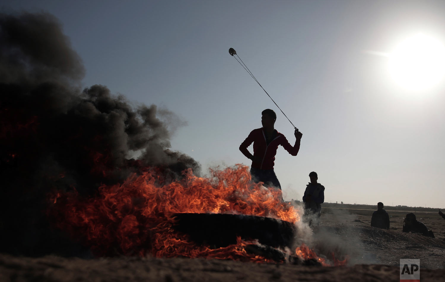 A Palestinian protester hurls stones toward Israeli soldiers during a protest near the Gaza Strip border with Israel, in eastern Gaza City, Saturday, March 31, 2018. (AP Photo/ Khalil Hamra)
