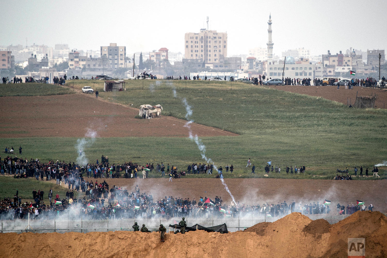 Israeli soldiers shoot tear gas toward Palestinian protesters as they gather on the Israel Gaza border, Friday, March 30, 2018. (AP Photo/Tsafrir Abayov)
