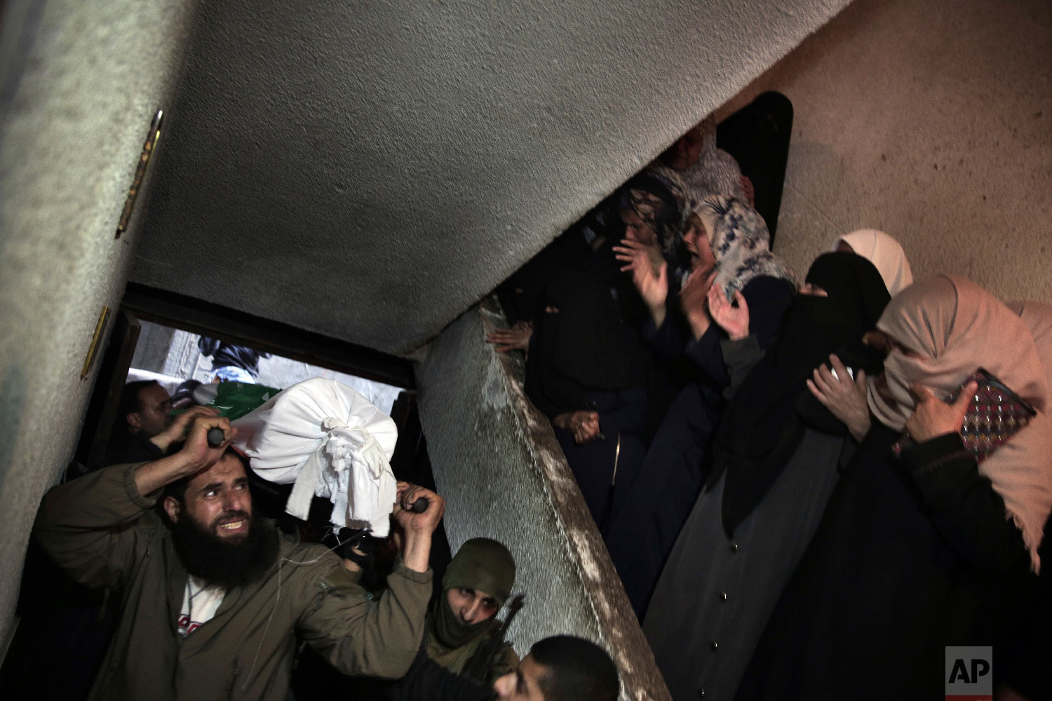 Relatives of Palestinian Ziyad Al-hawajri, react as mourners carry his body into the family house during his funeral in Nuseirat, central Gaza Strip, Thursday, March 22, 2018. Al-hawajri, is one of the two members of Hamas security forces who were killed Thursday during an operation to arrest suspects wanted for a bombing that targeted the visiting Palestinian premier's convoy in Gaza last week. (AP Photo/ Khalil Hamra)