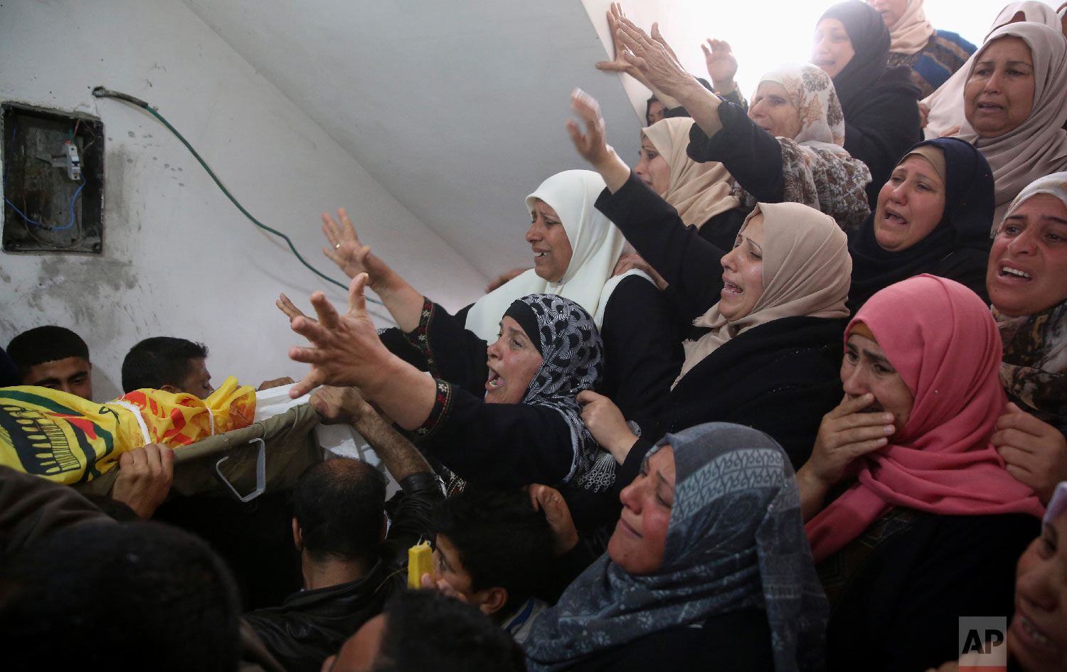 Relatives mourn over the body of Hamdan Abu Amsha, 23, during his funeral at the family house in Beit Hanoun, Gaza Strip, Saturday, March 31, 2018. Israel will target "terror organizations" in Gaza if violence along the territory's border with Israel drags on, the chief military spokesman warned Saturday, a day after thousands of Palestinians staged protests near the border fence. (AP Photo/Adel Hana)