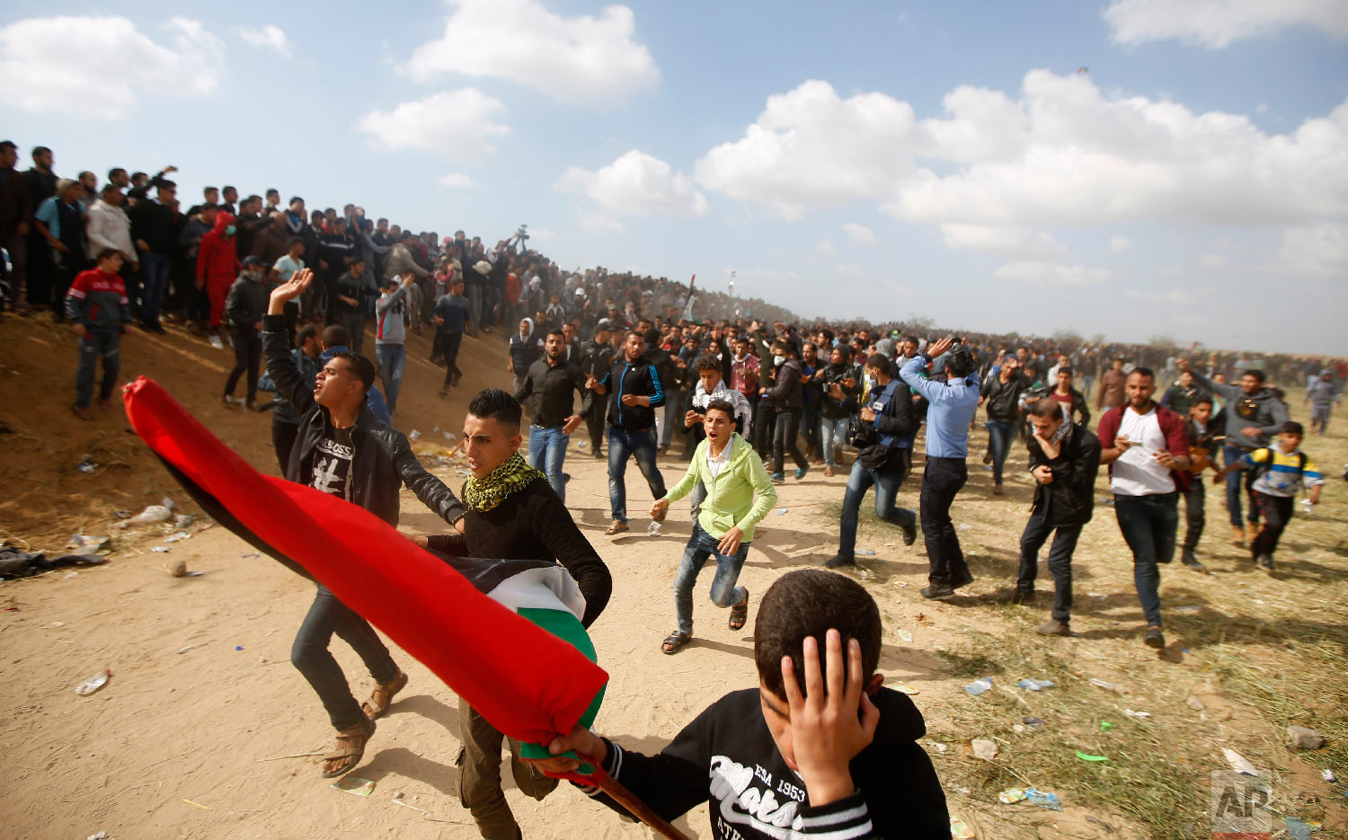  Palestinian protesters react while evacuate a wounded youth during clashes with Israeli troops along the Gaza Strip border with Israel, east of Khan Younis, Gaza Strip, Friday, March 30, 2018. (AP Photo/Adel Hana) 