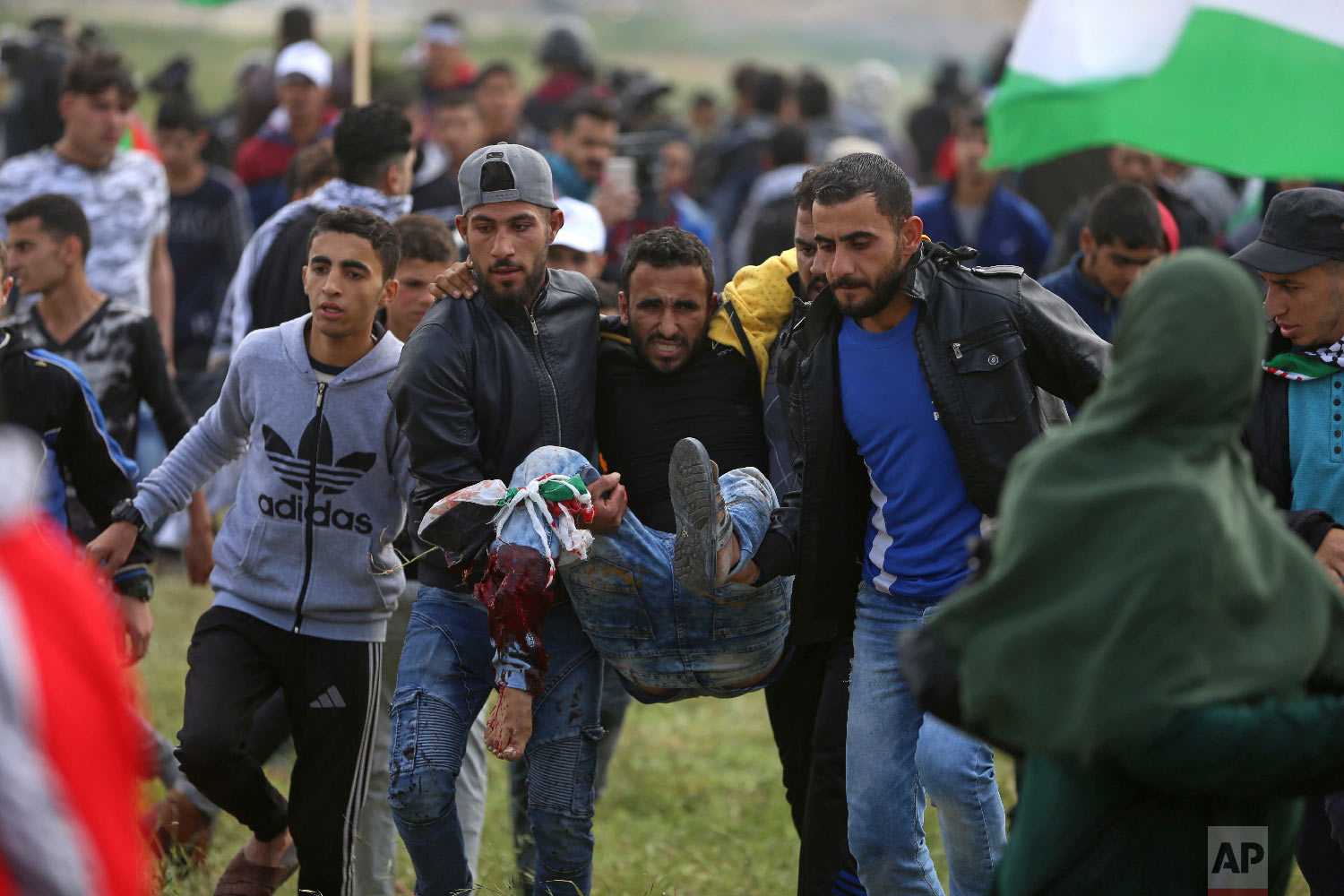 Palestinian protesters carry a wounded man was shot by Israeli troops during a demonstration near the Gaza Strip border with Israel, in eastern Gaza City, Friday, March 30, 2018. (AP Photo/ Khalil Hamra)