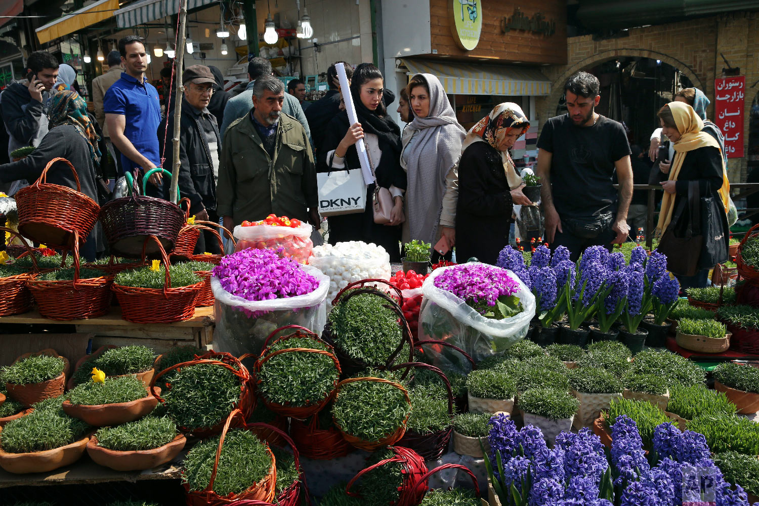 In this Monday, March 19, 2018 photo, Iranians shop for hyacinths, garlic, sprouts and other items used to celebrate the Iranian New Year, ahead of the holiday, at the Tajrish traditional bazaar in northern Tehran, Iran. (AP Photo/Vahid Salemi)