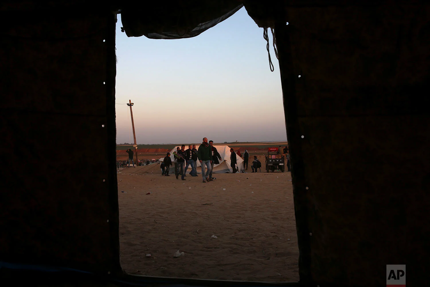 Palestinians walk between their family tents which set up in front the Gaza Strip border with Israel, east of Beit Lahiya, Gaza Strip, Saturday, March 31, 2018. (AP Photo/Adel Hana)