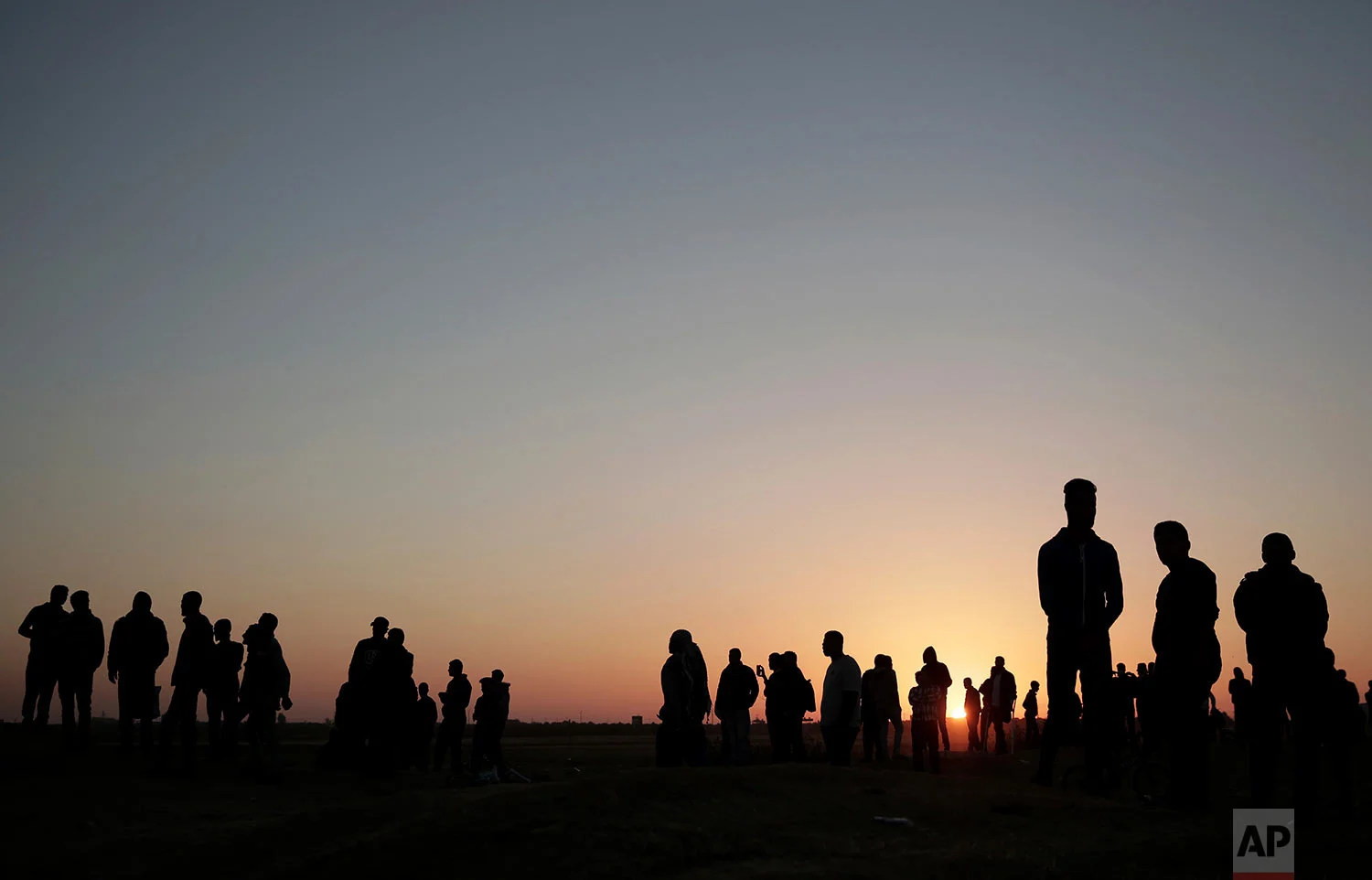 The sun sets over Palestinian protesters gathered at the Gaza Strip border with Israel, in eastern Gaza City, Sunday, April 1, 2018. (AP Photo/Khalil Hamra)