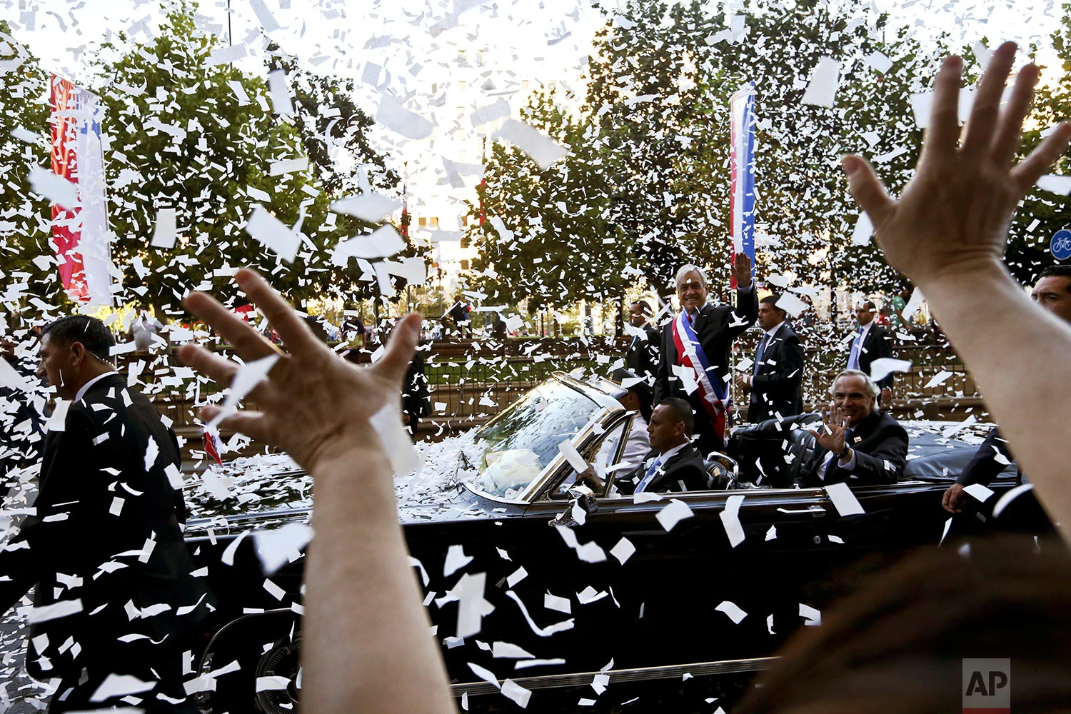 Chile's President Sebastian Pinera waves from under a shower of confetti as he makes his way to La Moneda presidential palace on the day of his inauguration in Santiago, Chile, March 11, 2018. Pinera returned to Chile's presidency, after his first term from 2010 to 2014. (AP Photo/Esteban Felix)