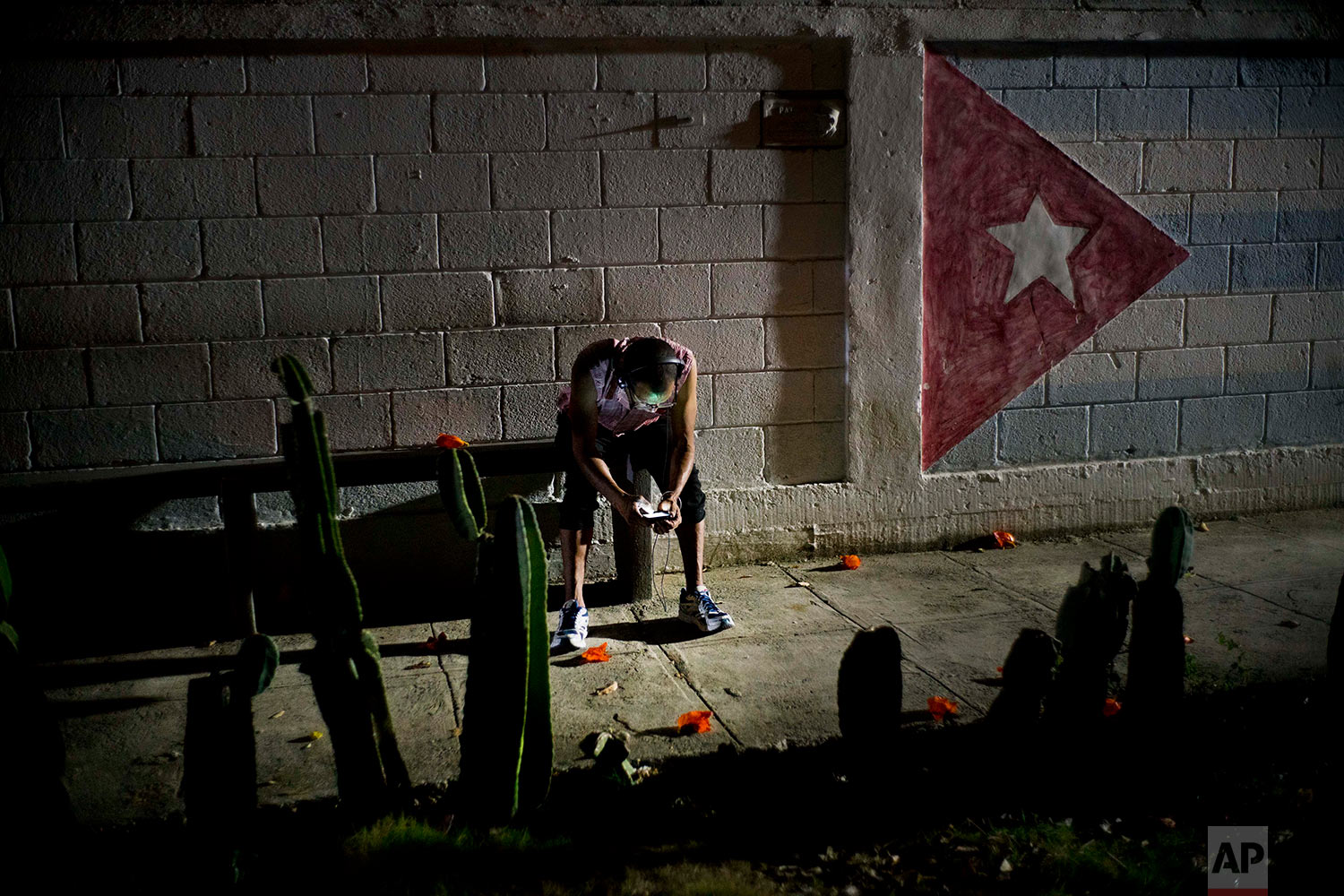 In this April 14, 2018 photo, Lazaro Rodriguez, 42, connects his cell phone at a public internet hot spot at night in Havana, Cuba. Lazaro, who studied baking and is currently working in maintenance, said he’s seen very positive changes in the economy in recent years, and would like to see development continue. “The generation that comes after me will have much more. I lived ‘the special period’ in the 90s, and the country is still blocked,” referring to the U.S. embargo. (AP Photo/Ramon Espinosa)