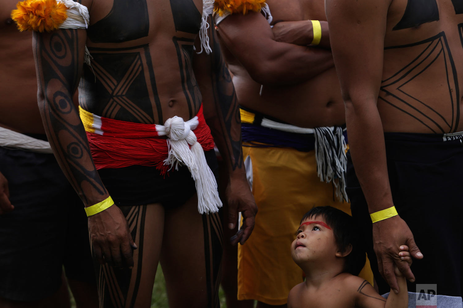  A Kuikuro indigenous toddler looks up at the adults inside a camp coined "Free Land," at the start of an annual gathering by Brazil's indigenous peoples in Brasilia, Brazil, Monday, April 23, 2018. Hundreds of indigenous Brazilians are setting up ca