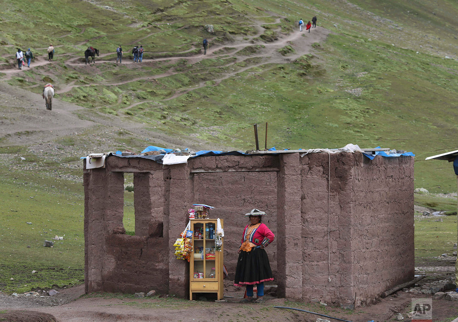  In this March 2, 2018 photo, an Andean woman sells candies, water and chips, on the route to Rainbow Mountain, in Pitumarca, Peru. (AP Photo/Martin Mejia) 