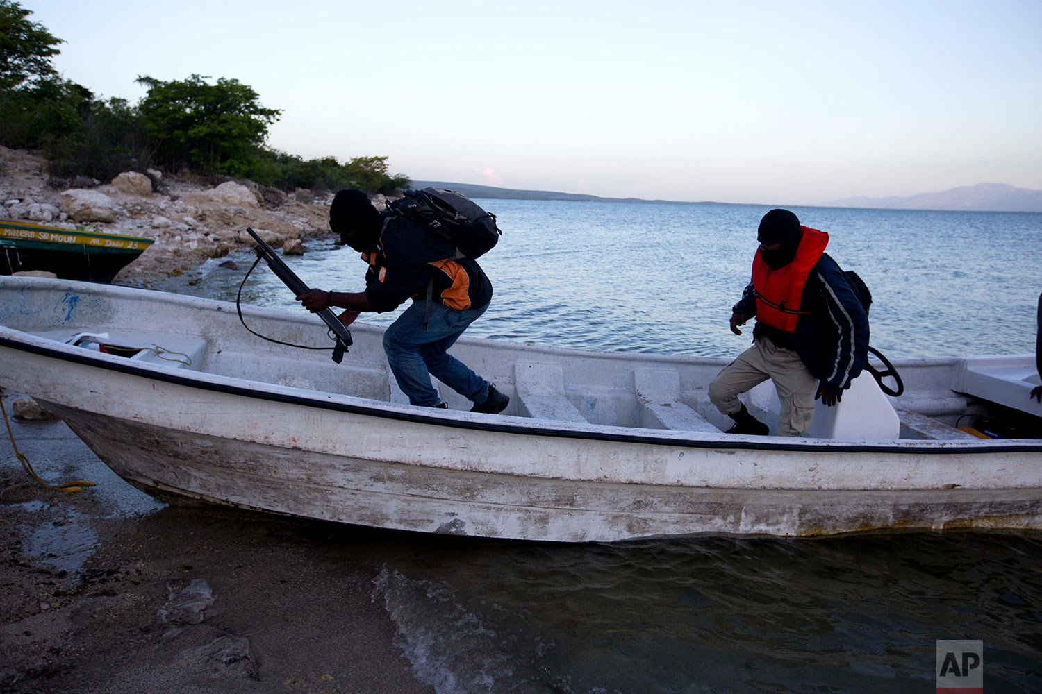  In this April 17, 2018 photo, two Taino Aqua Fish farm security guards return to shore at dawn after sleeping on the lake in two different locations to keep watch over fish cages on Lake Azuei in Fond Parisien, Haiti. The company has 60 employees, i