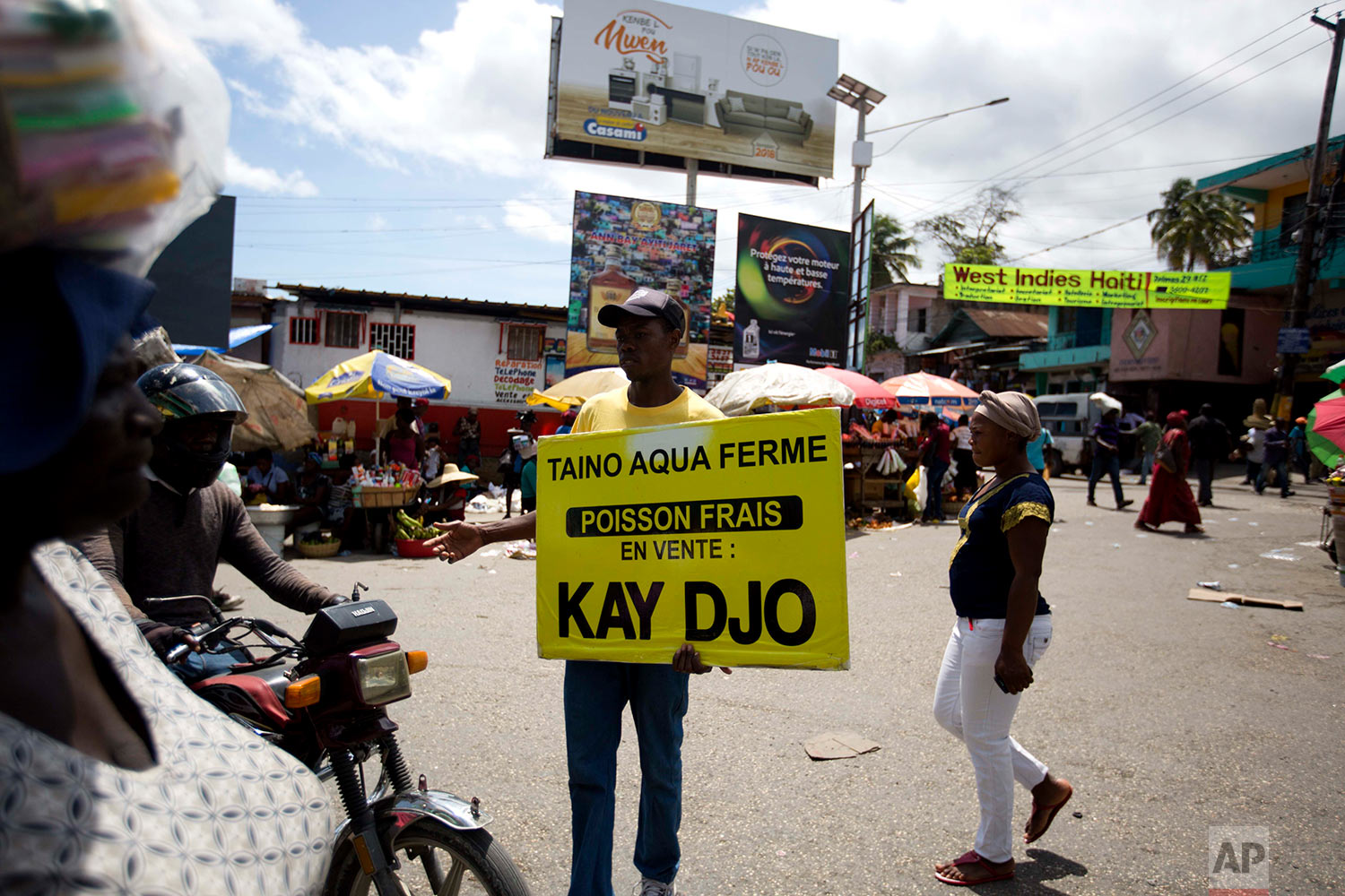  In this April 27, 2018 photo, Taino Aqua Fish worker Bernard Pierre Emil advertises that their tilapia fish can be bought at a stall outside the Kay Djo supermarket in Petion-Ville, Haiti. Taino markets its crop, which can reach 20,000 pounds a week