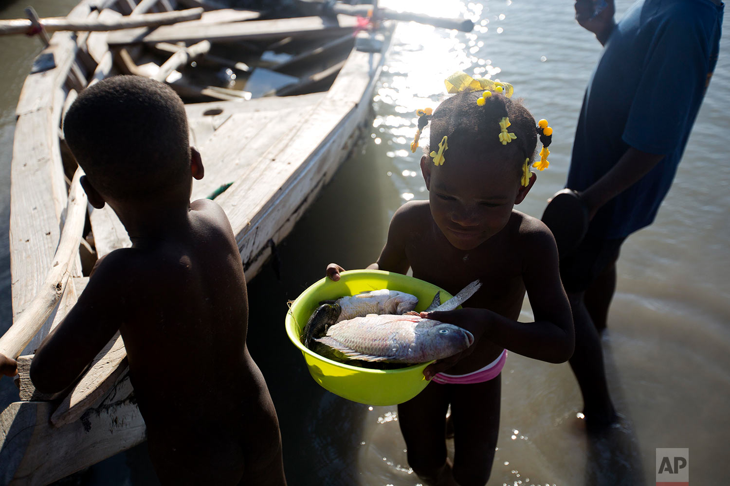  In this April 26, 2018 photo, Gerline Louis, the six-year-old daughter of fisherman Miguel Louis, carries the five fish her father caught in Lake Azuei in Fond Parisien, Haiti. Most people in this small border town, like Louis' family, get most of t