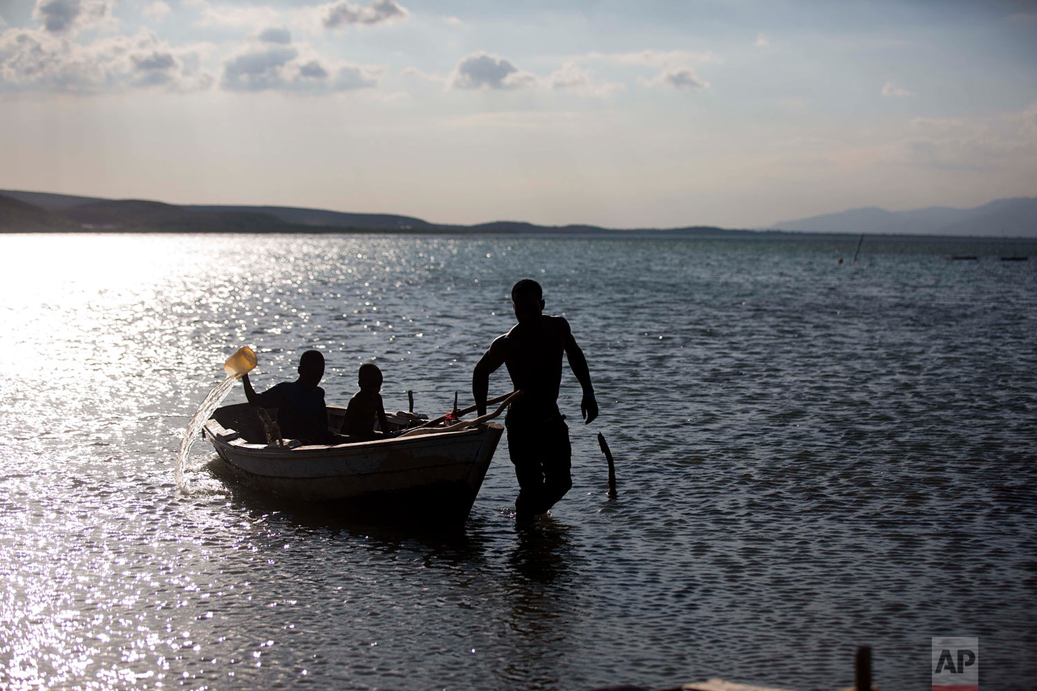  In this April 26, 2018 photo, fisherman Miguel Louis pulls his children in his boat after checking on his nets set up in Lake Azuei in Fond Parisien, Haiti. His 12-year-old son Dabens Louis bales water from the old, wooden boat, due to a small hole.