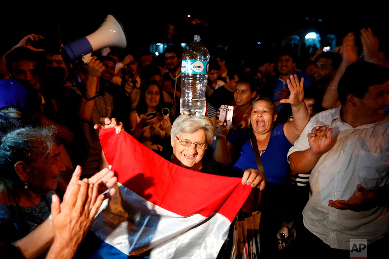 In this April 24, 2018 photo, a woman balances a bottle of water on her head as she performs a traditional dance during a gathering by supporters of presidential candidate Efrain Alegre, who lost the election, to protest what they believe was electoral fraud in recent general elections, outside the Superior Tribunal of Electoral Justice, a court that manages election cases, in Asuncion, Paraguay. Alegre declined to concede, saying he would wait for the final count, though electoral officials said there were not enough ballots left to be counted to change the result. The new president, Mario Abdo Benitez of the governing Colorado Party, begins a five-year term Aug. 15. (AP Photo/Jorge Saenz)