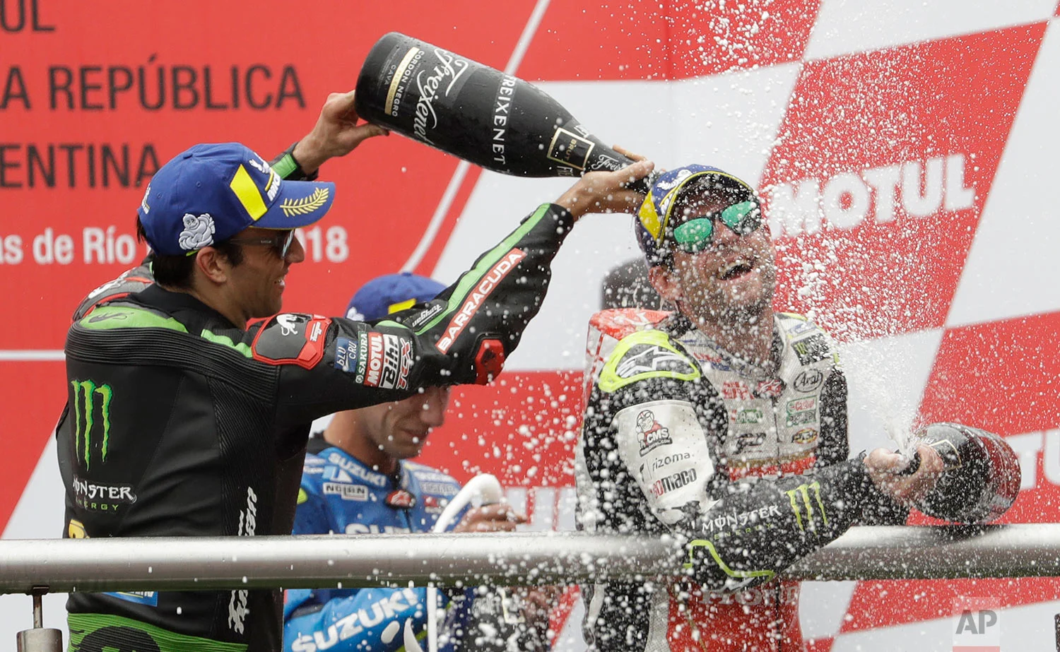 MotoGP first place winner, Great Britain's Cal Crutchlow of Honda, right, is sprayed by second place winner, France's Johann Zarco of Yamaha, on the awards podium during Argentina's Motorcycle Grand Prix at the Termas de Rio Hondo circuit in Argentina, Sunday, April 8, 2018. (AP Photo/Natacha Pisarenko)