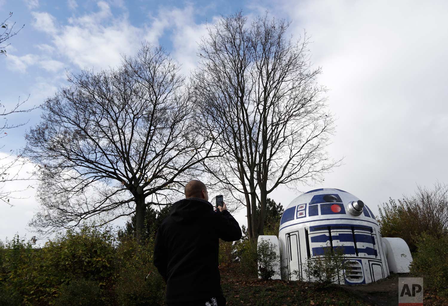  A man takes a photo of an air ventilation turned by an unknown street artist into Star Wars'  R2-D2  in a park in Prague, Czech Republic, Saturday, Oct. 28, 2017. According to Prague 2 district mayor, Jana Cernochova, the robot is there to stay. "We