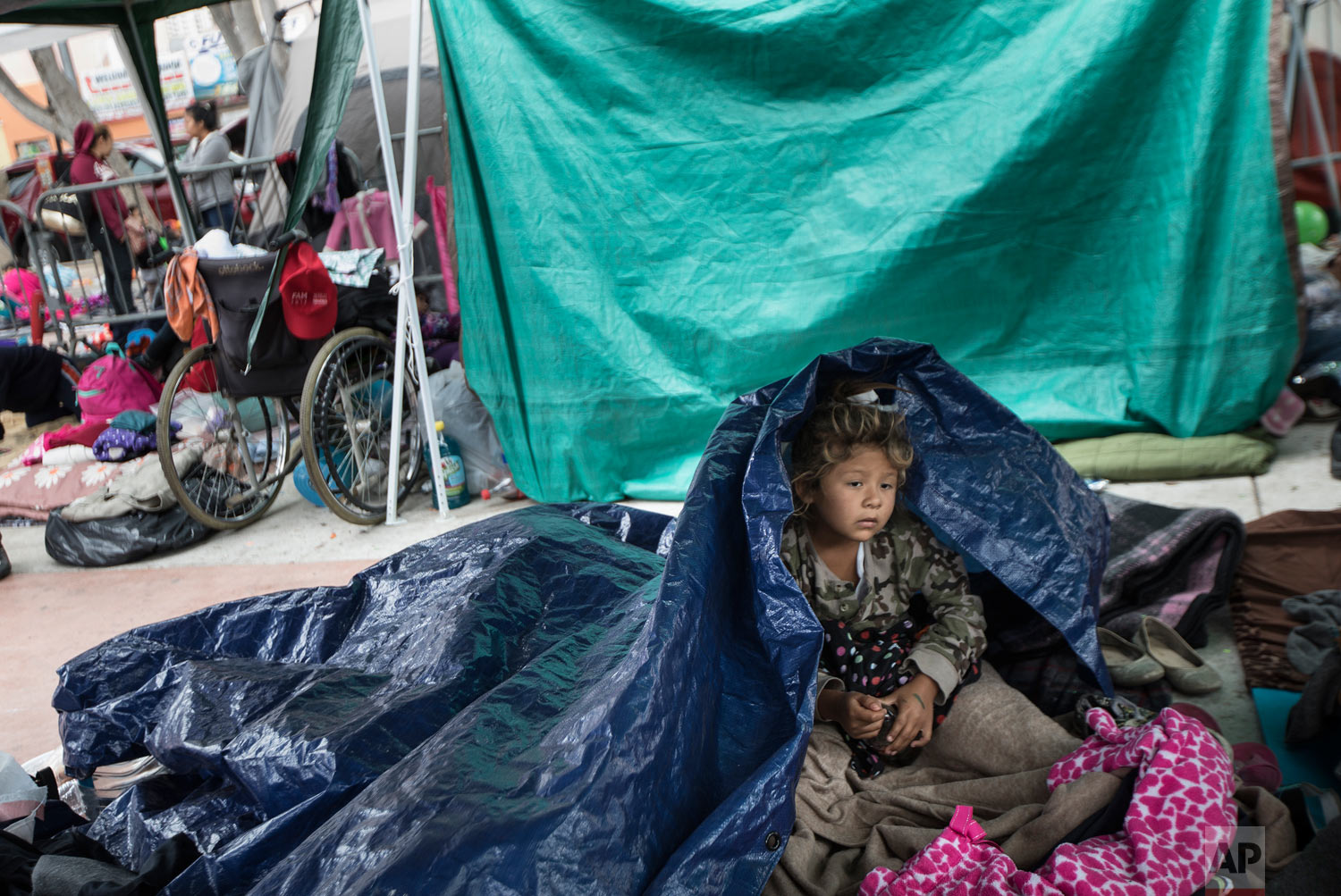 A girl who traveled with a caravan of Central American migrants awakens where the group set up camp to wait for access to request asylum in the U.S., outside the El Chaparral port of entry building at the U.S.-Mexico border in Tijuana, Mexico, Tuesd