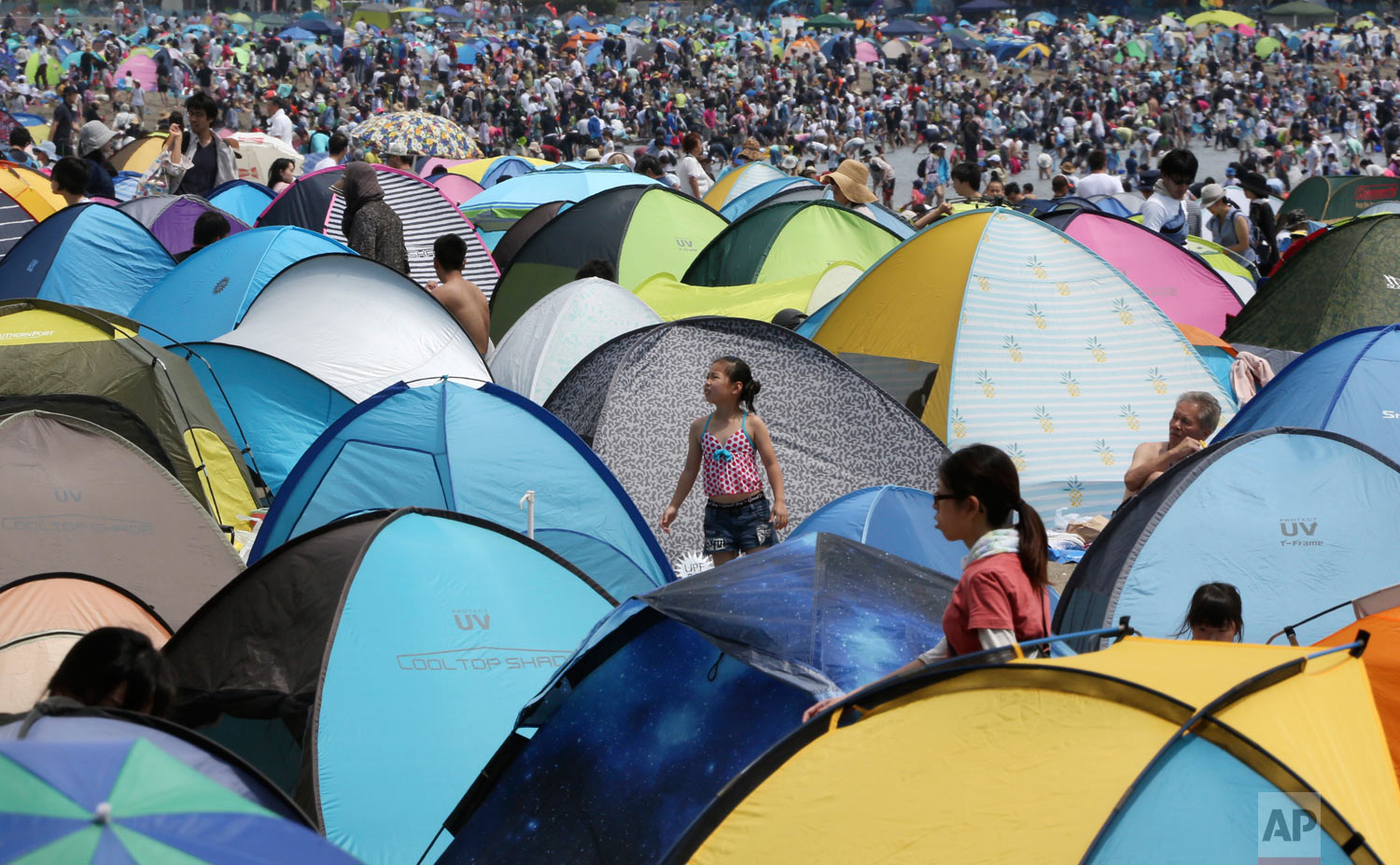 Holiday makers walk past tents on the beach to hunt for clams in Yokohama, near Tokyo, Monday, April 30, 2018. (AP Photo/Koji Sasahara)
