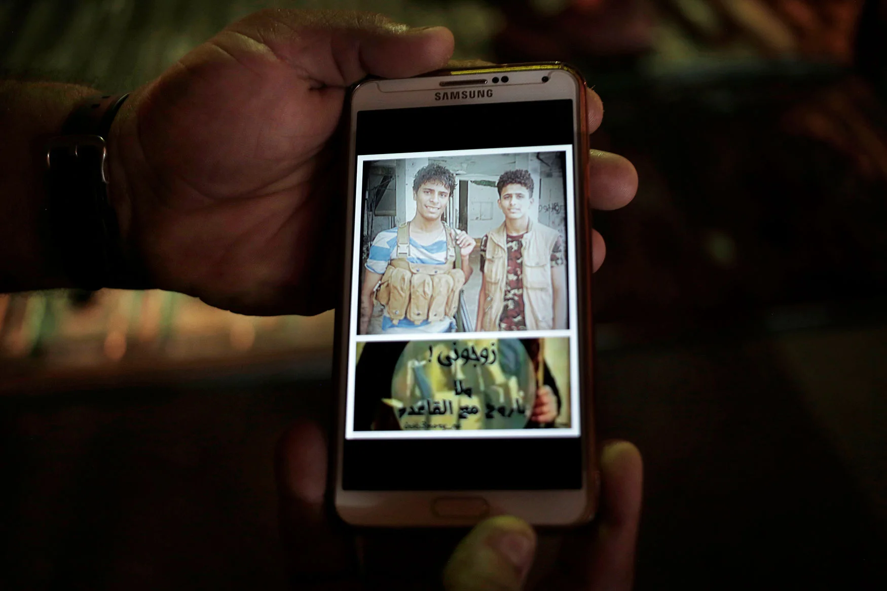 This Feb. 17, 2018 photo, shows a mobile photo of then 18-year old Ahmed Saleh, left, with his friend during the '2015 battle of Aden' and Arabic that reads, "marry me or I will go with Al Qaida," in Aden, Yemen. (AP Photo/Nariman El-Mofty)