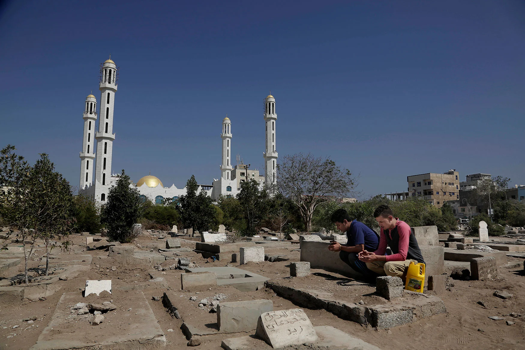 In this Feb. 18, 2018 photo, 21-year olds and best friends Osama Ahmed, right, and Ahmed Saleh, who both fought during the '2015 battle of Aden' pray in front of the tombstone of their friend who was killed during the war, at the Al-Rahma graveyard in Aden, Yemen. (AP Photo/Nariman El-Mofty)