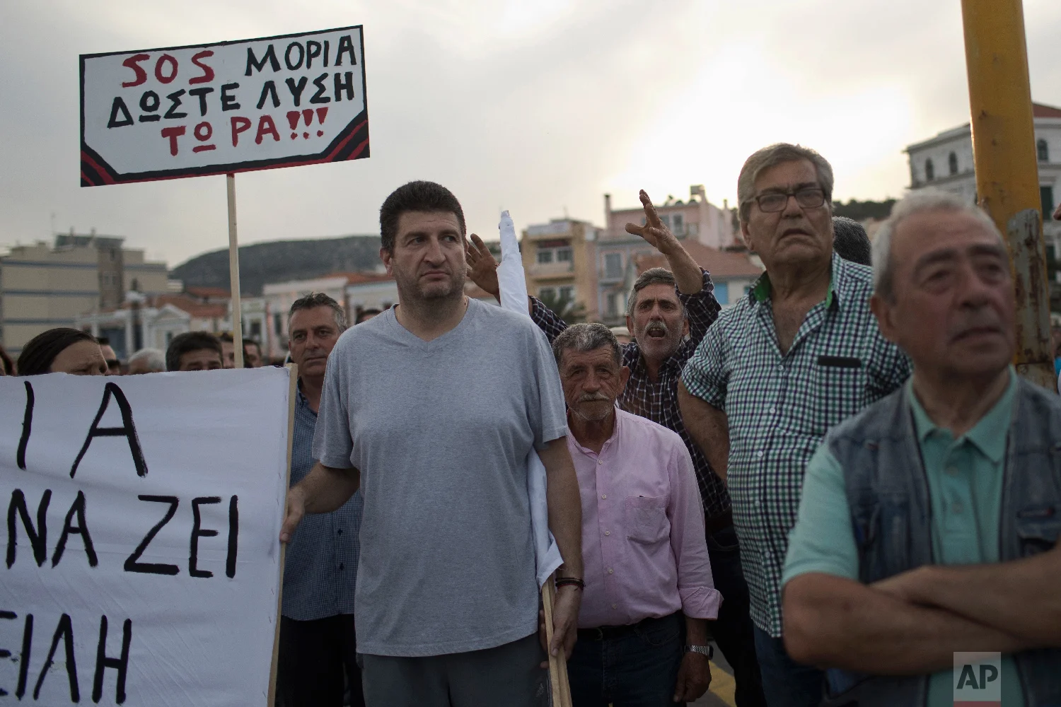 Islanders hold a placard which reads in Greek "SOS Moria. Solution now" referring to the Moria refugee camp, in a protest during a visit by Greek Prime Minister Alexis Tsipras on the northeastern Aegean island of Lesbos on Thursday, May 3, 2018 "(Migrants) enter illegally, they have to leave" one of the protesters shouted. Islanders are angry at Greek and European Union migration policy, which has left thousands of people stranded on the island. (AP Photo/Petros Giannakouris)