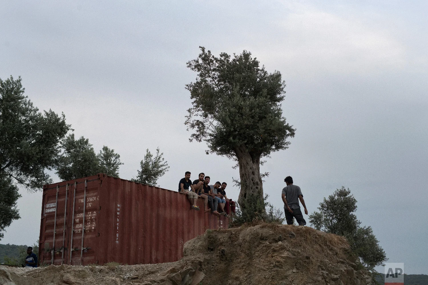 Refugees and migrants sit on the top of a container at a makeshift camp outside Moria on the northeastern Aegean island of Lesbos, Greece on Saturday May 5, 2018. (AP Photo/Petros Giannakouris)