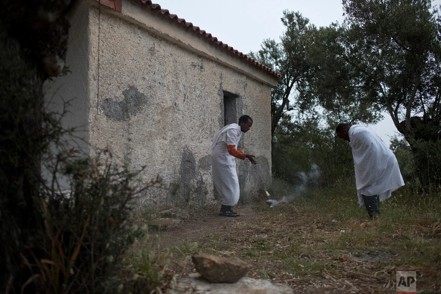 An Ethiopian Christian priest blesses another refugee during a Sunday mass outside an orthodox church near Moria camp in the island of Lesbos, Greece on Sunday, May 6, 2018. (AP Photo/Petros Giannakouris)