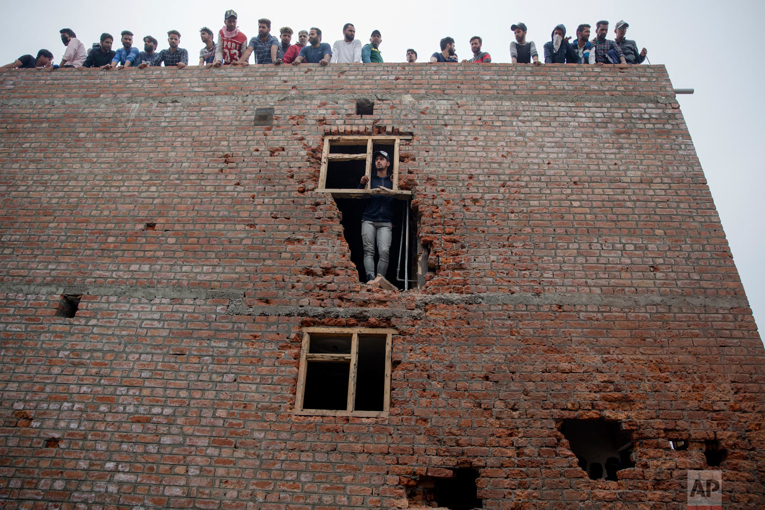 Kashmiri men inspect a house, damaged during a gun battle where suspected rebels were holed up, in Srinagar, Indian-controlled Kashmir, on Saturday, May 5, 2018. Fierce clashes erupted when residents in solidarity with the rebels tried to march to the gunbattle site. A vehicle belonging to Indian troops ran over and killed a man as protesters clashed with government forces, residents said. (AP Photo/Dar Yasin)
