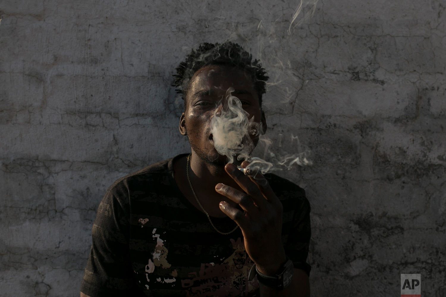  Malawian migrant Jonas smokes marihuana on the rooftop of an abandoned building. March 29, 2018. (AP Photo/Bram Janssen) 