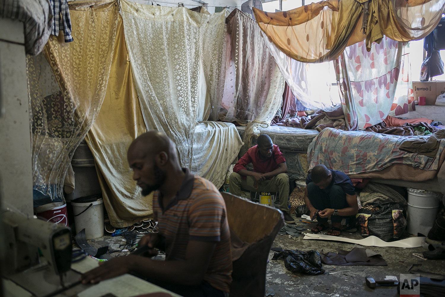  Malawian migrant shoe makers work inside their bedroom. March 29, 2018. (AP Photo/Bram Janssen) 