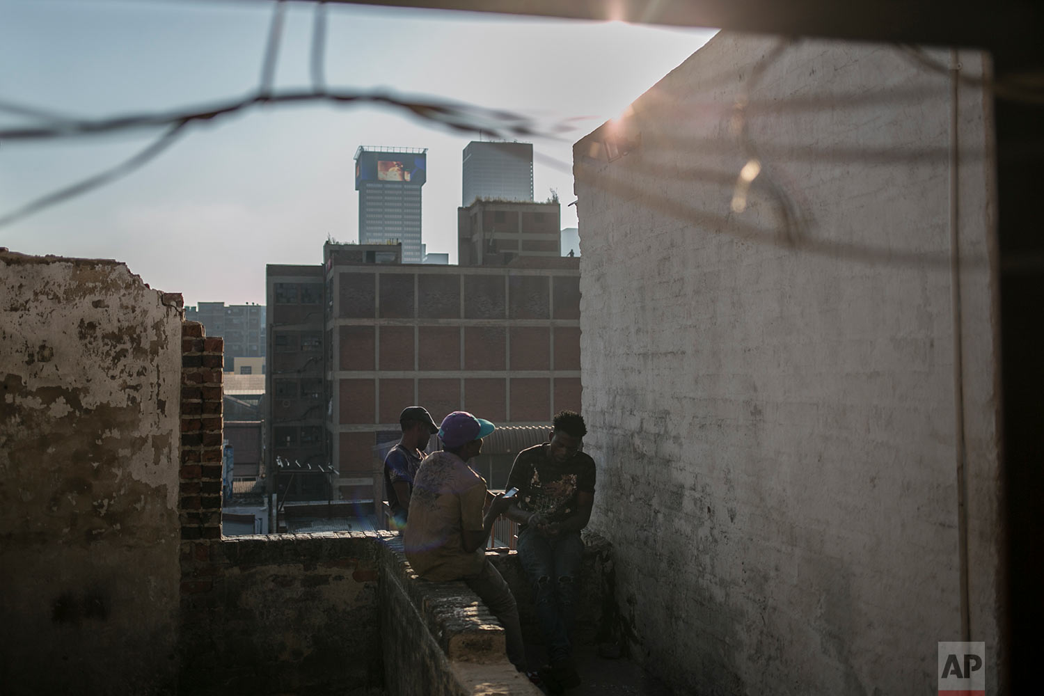  Malawian migrants sit on the rooftop of an abandoned building. March 29, 2018. (AP Photo/Bram Janssen) 