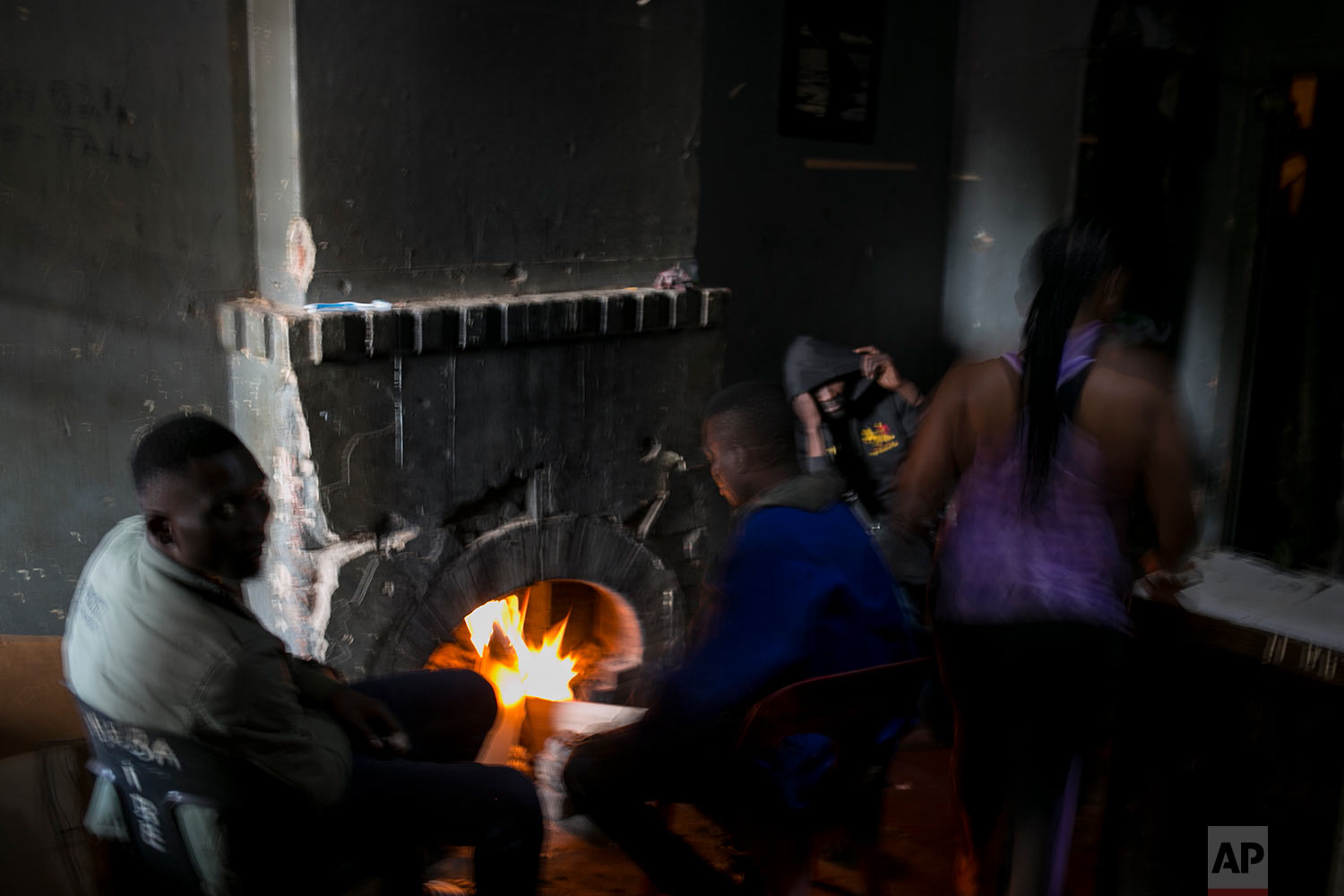  People warm themselves by a fire place in an abandoned building. (AP Photo/Bram Janssen) 