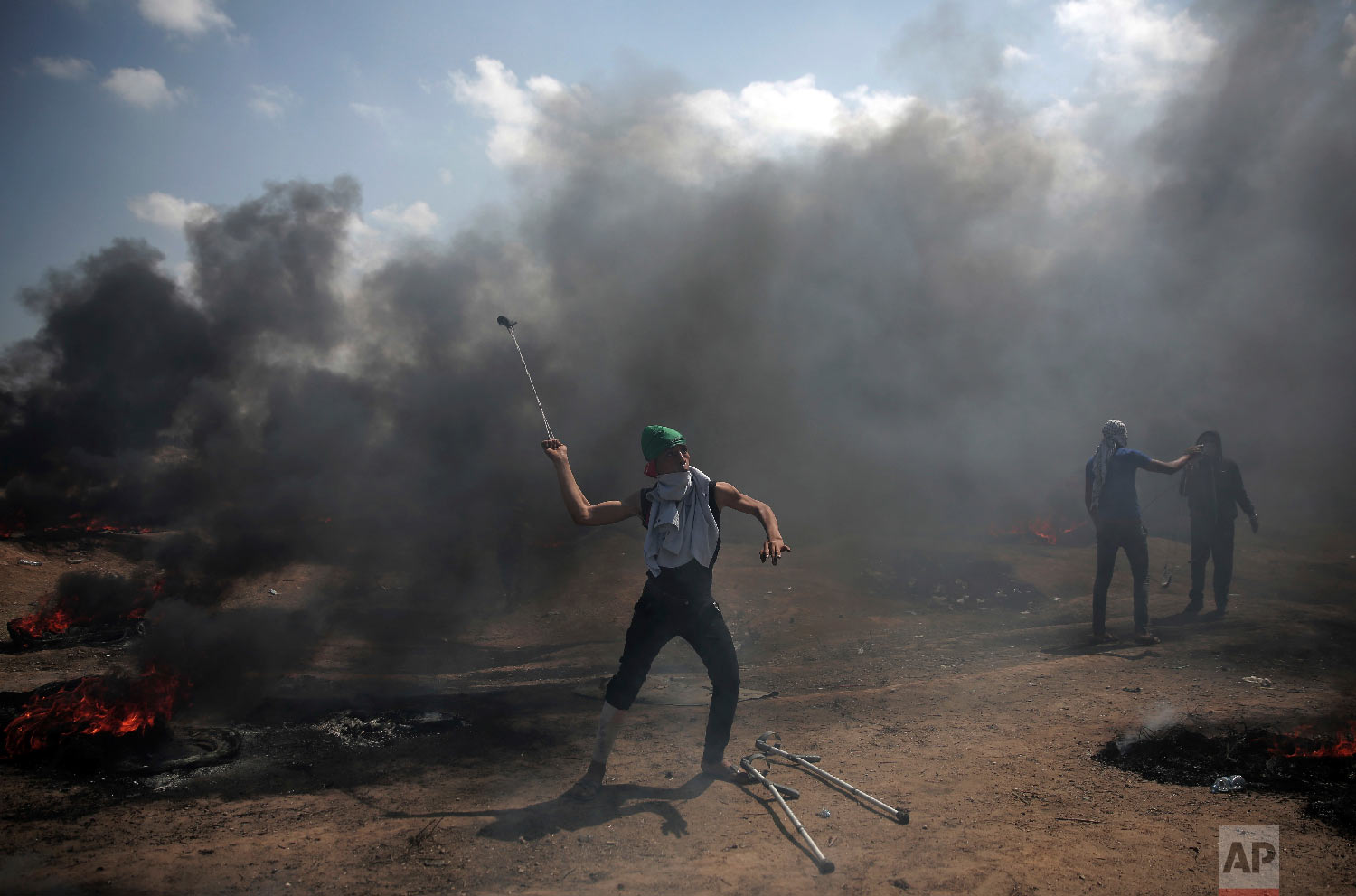 Palestinian protesters hurl stones at Israeli troops during a protest on the Gaza Strip's border with Israel, Monday, May 14, 2018. (AP Photo/Khalil Hamra)