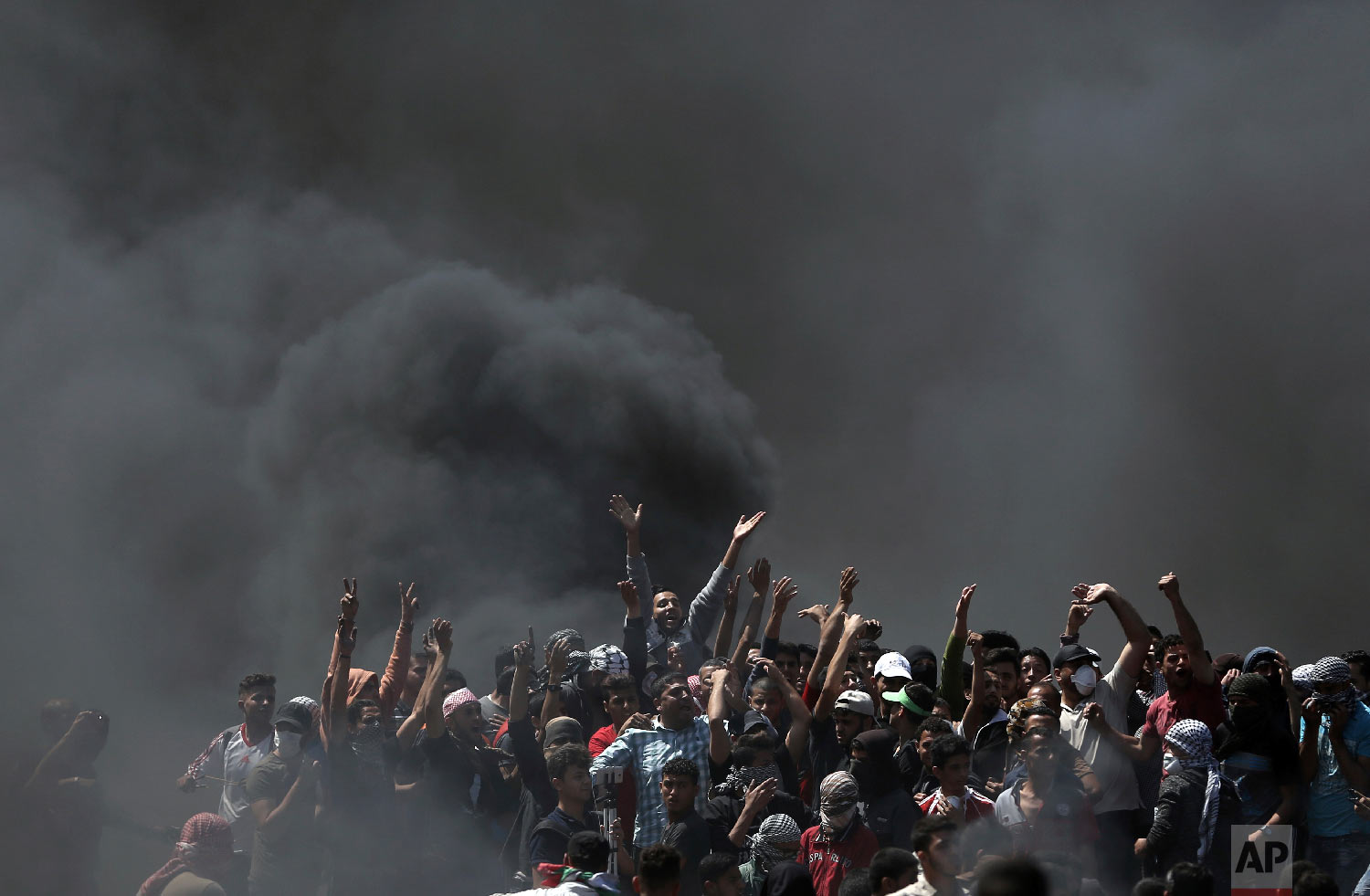 Palestinian protesters chant slogans as they burn tires during a protest on the Gaza Strip's border with Israel, Monday, May 14, 2018. (AP Photo/Khalil Hamra)