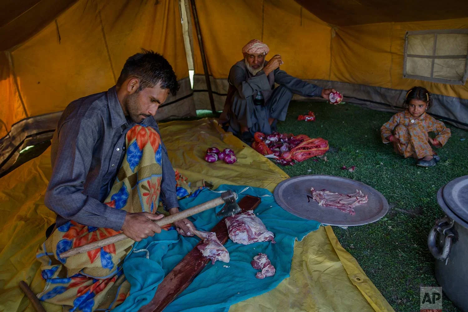 In this May 10, 2018, photo, Mohammad Aslam Khan, a Kashmiri nomadic Bakarwal cuts goat meat for a wedding feast at a camp in outskirts of Srinagar, Indian controlled Kashmir. (AP Photo/Dar Yasin)