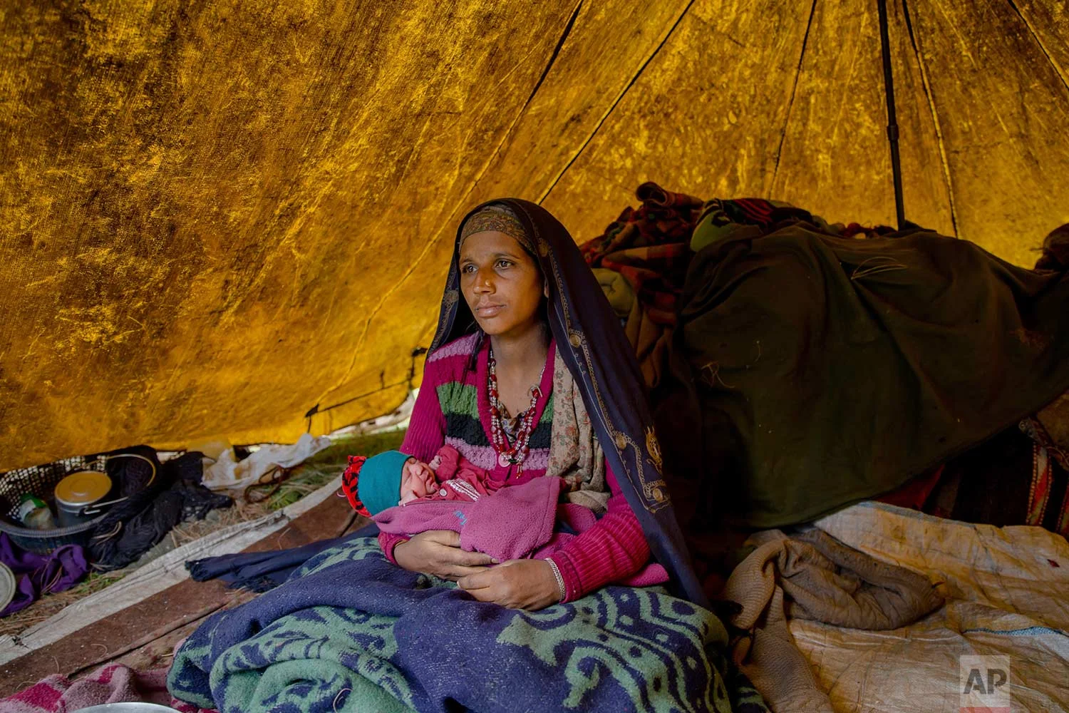 In this May 9, 2018, photo, Nasreen Bano, a Kashmiri nomadic Bakarwal woman poses for pictures along with her new born baby girl inside her tent at a temporary camp in Dubgan, 70 kilometers (43 miles) south of Srinagar, Indian controlled Kashmir. (AP Photo/Dar Yasin)