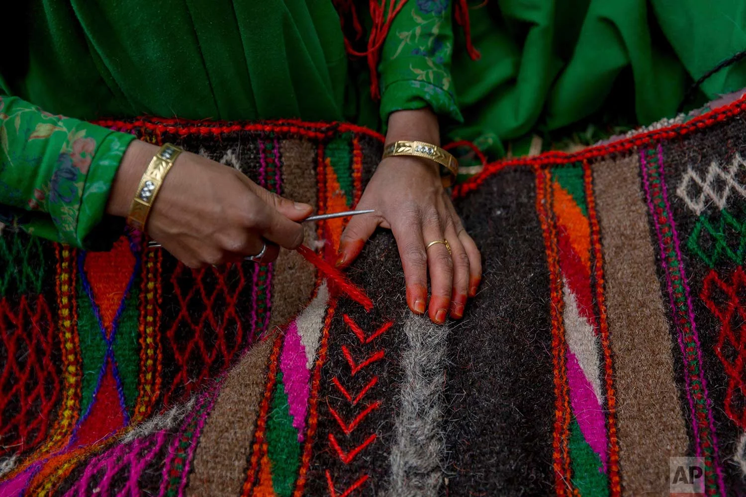 In this May 9, 2018, photo, a Kashmiri nomadic Bakarwal woman decorates a blanket made from goat hair outside her tent in Newa, 29 kilometers (18 miles) south of Srinagar, Indian controlled Kashmir. (AP Photo/Dar Yasin)