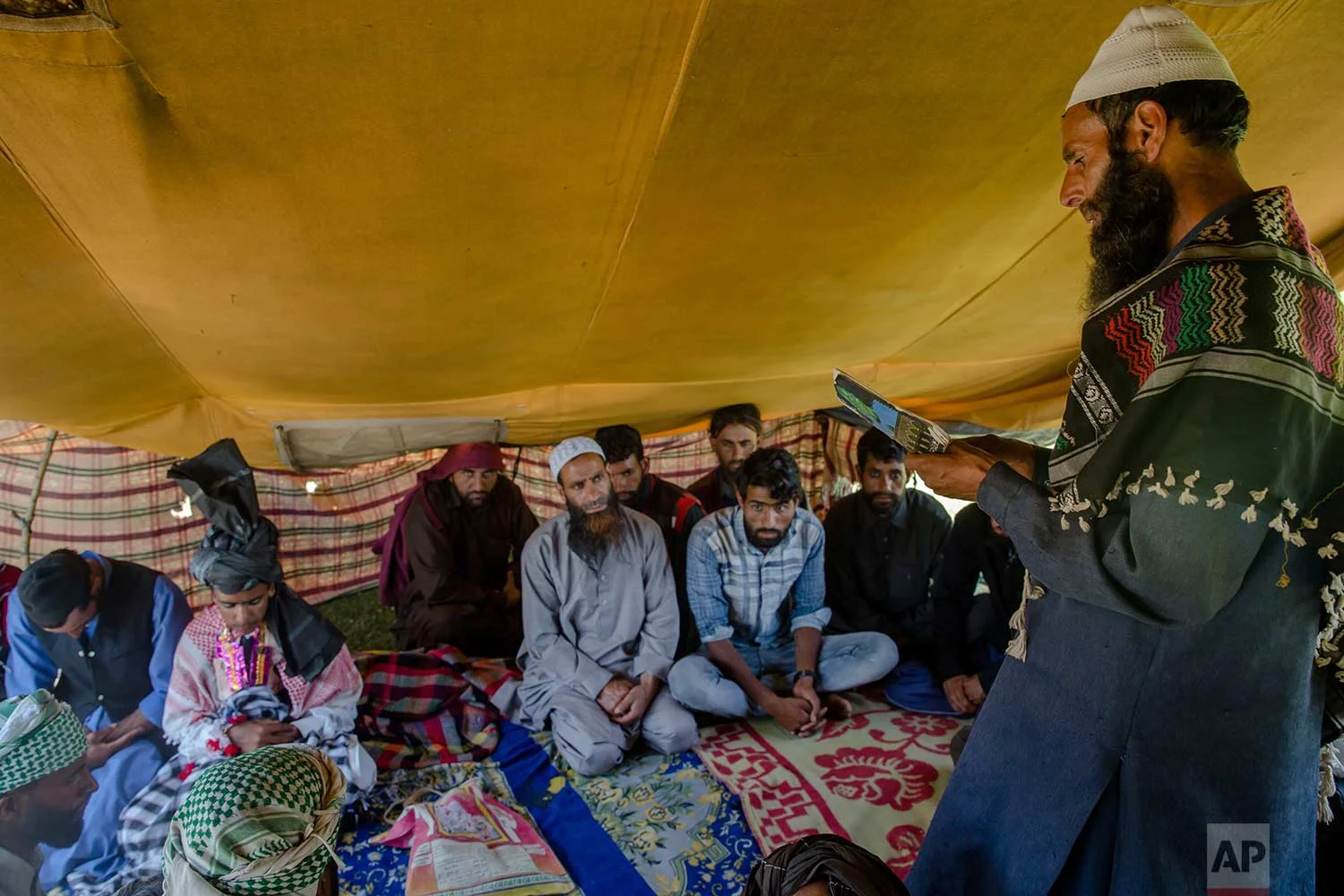 In this May 11, 2018, photo, Kashmiri Bakarwal nomads listen to a sermon delivered by a cleric during a marriage ceremony at a camp in the outskirts of Srinagar, Indian controlled Kashmir. (AP Photo/Dar Yasin)