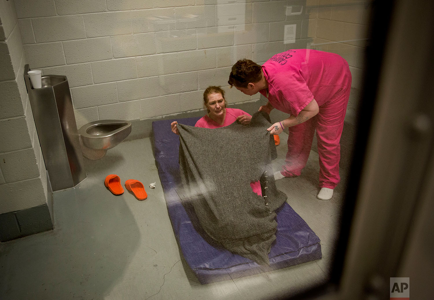  Mary Sammons helps cover Linda Green with a blanket as she lies down in the Campbell County Jail after being arrested on charges of public intoxication, a parole violation, in Jacksboro, Tenn., Thursday, March 29, 2018. (AP Photo/David Goldman) 