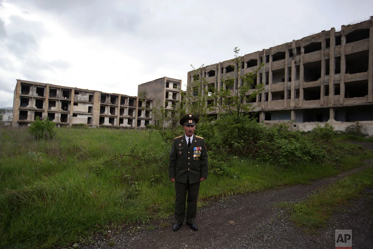 In this Thursday, May 10, 2018, Armenian Garnik Avanesyan, veteran Lieutenant Colonel poses in front of destroyed buildings during the war in Shusha town. (AP Photo/Thanassis Stavrakis)