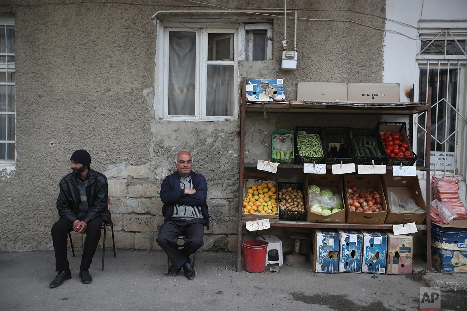 In this Tursday, May 10, 2018, a fruit vendor with his friend sit outside his shop in Stepanakert. AP Photo/Thanassis Stavrakis)