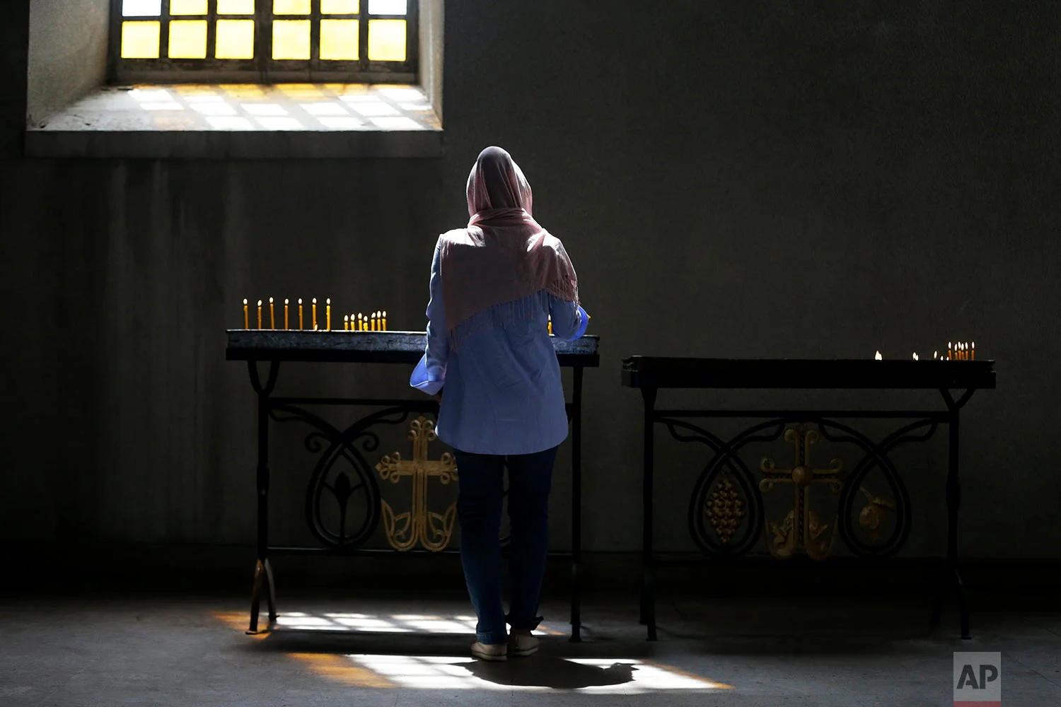 In this Thursday, May 10, 2018, a woman lights a candle at a church in Shusha town. (AP Photo/Thanassis Stavrakis)