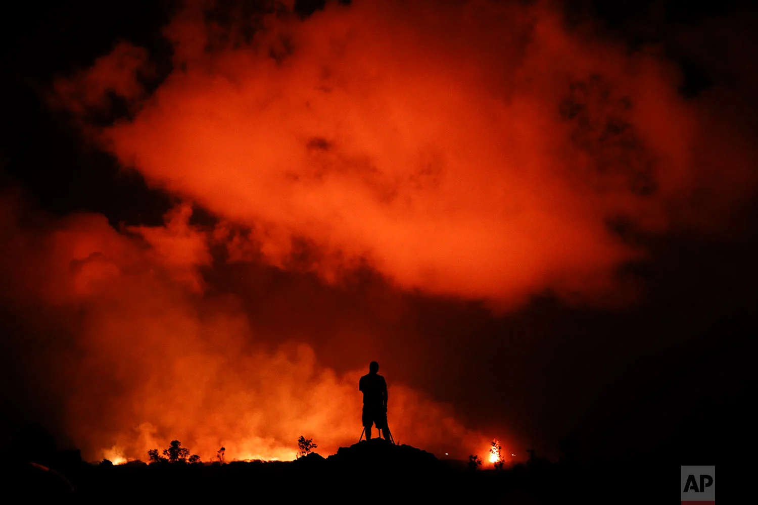 Peter Vance, 24, photographs lava erupting in the Leilani Estates subdivision near Pahoa, Hawaii, May 18, 2018. (AP Photo/Jae C. Hong)