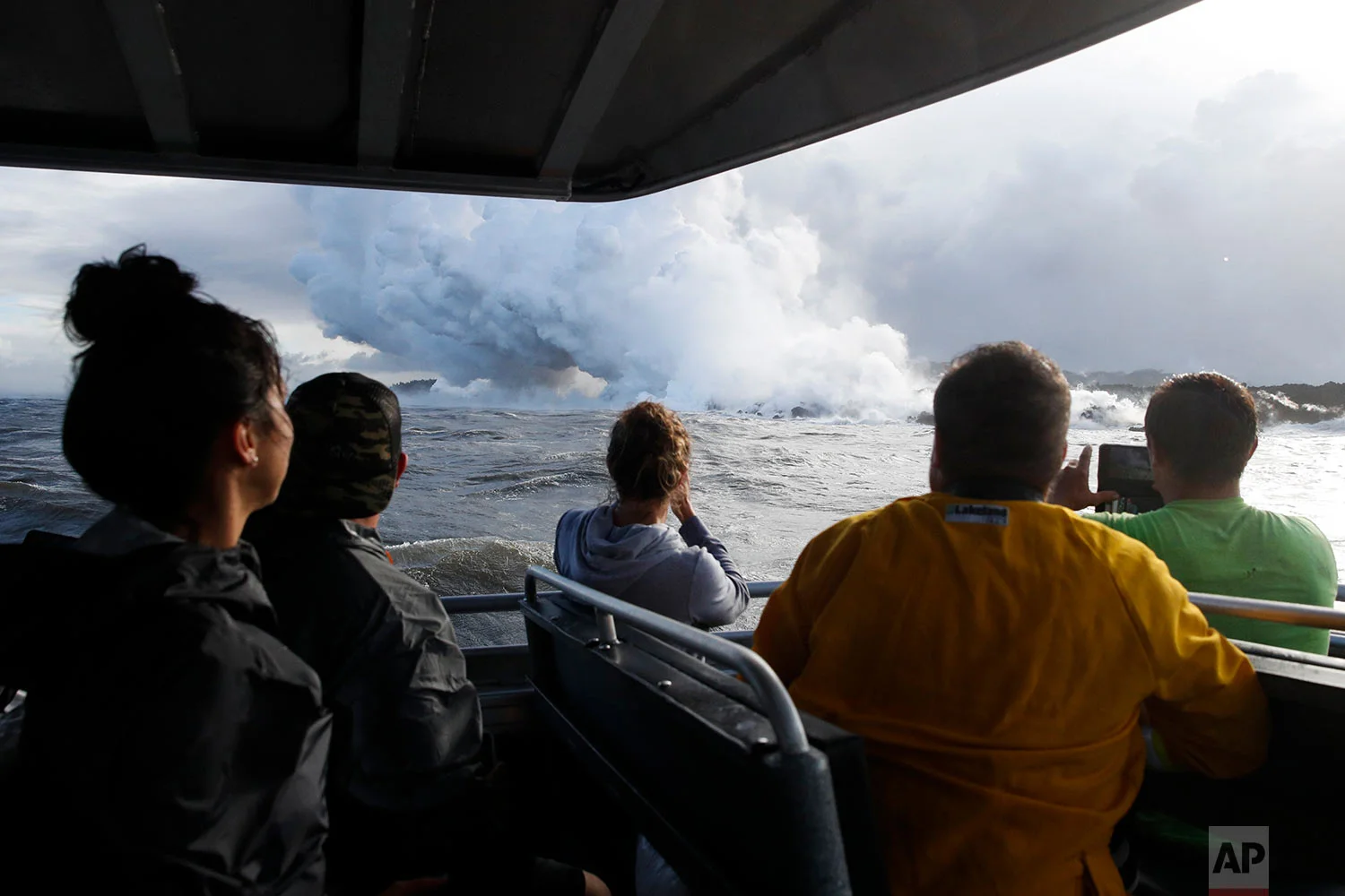People watch a plume of steam as lava enters the ocean near Pahoa, Hawaii, May 20, 2018. (AP Photo/Jae C. Hong)