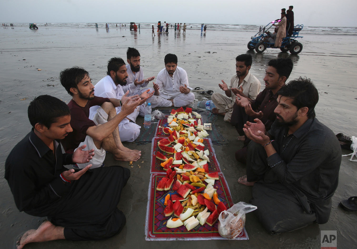 People pray prior to breaking their Ramadan fast at Clifton Beach in Karachi, Pakistan, Saturday, May 19, 2018. Muslims throughout the world are celebrating Ramadan, the holiest month in the Islamic calendar, refraining from eating, drinking, smokin