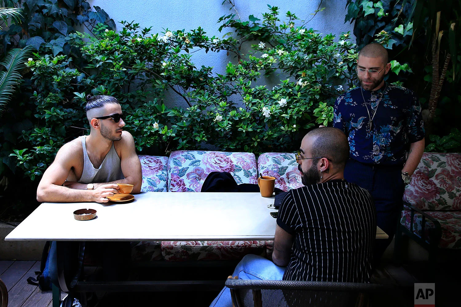 In this picture taken Saturday, May 12, 2018, Elias, 24, right who goes by the stage name of Melanie Coxxx drinks coffee with his friends at a restaurant during the launch event of Beirut Pride week in Beirut, Lebanon. (AP Photo/Hassan Ammar)
