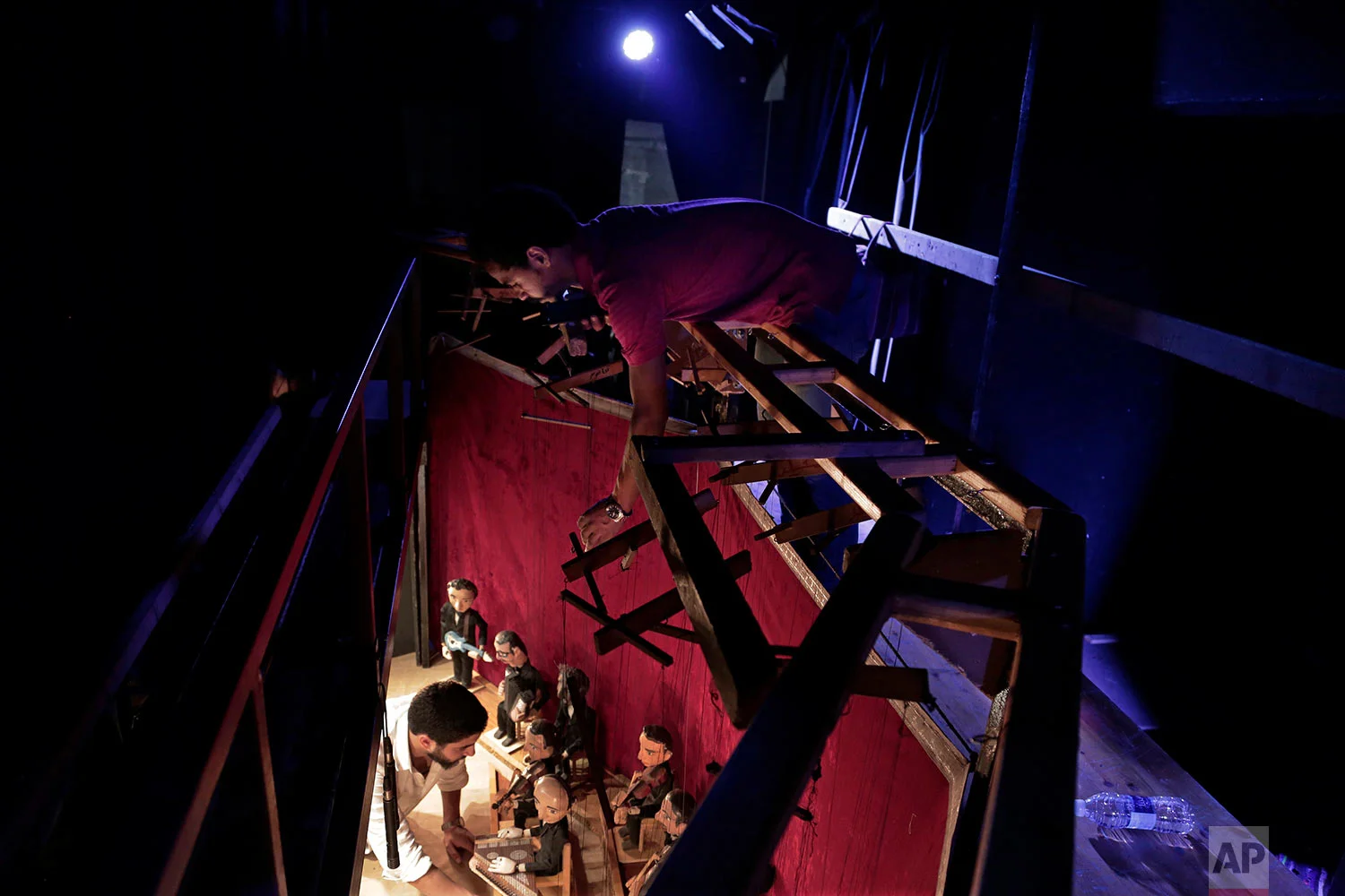 Egyptian marionette artist Mohamed Fawzi Bakkar, top, prepares puppets during a performance at the El Sawy Cultural Center, in Cairo, Egypt, May 3, 2018. (AP Photo/Nariman El-Mofty)