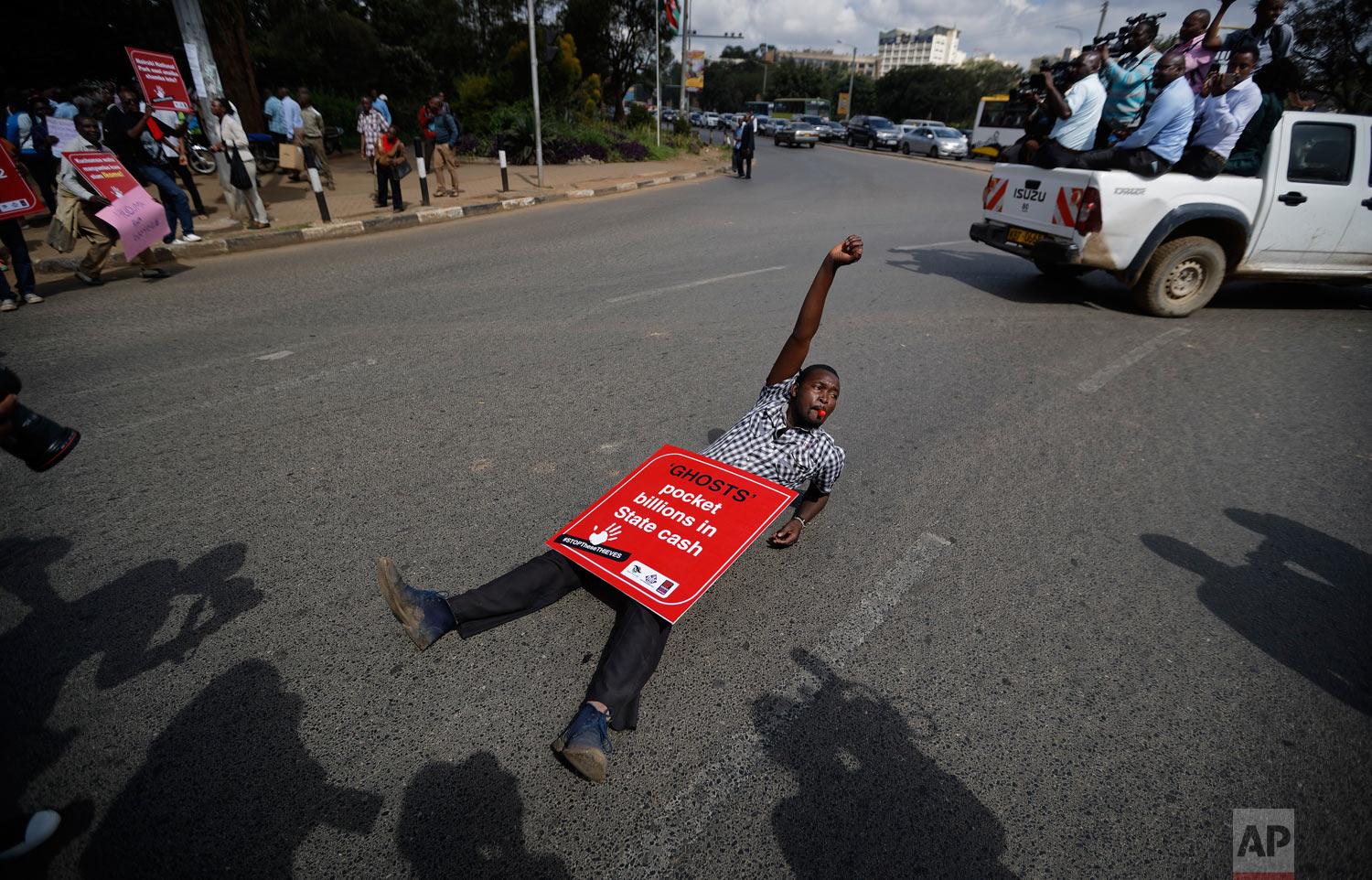 A protester lies down on the street during an anti-corruption demonstration by hundreds of protesters who marched to the Parliament and Supreme Court in downtown Nairobi, Kenya, Thursday, May 31, 2018. Kenya's leader is under increasing pressure as outrage grows over a number of corruption scandals involving tens of millions of dollars revealed in recent weeks around the ministries of health, energy, agriculture, public service and youth. (AP Photo/Ben Curtis)